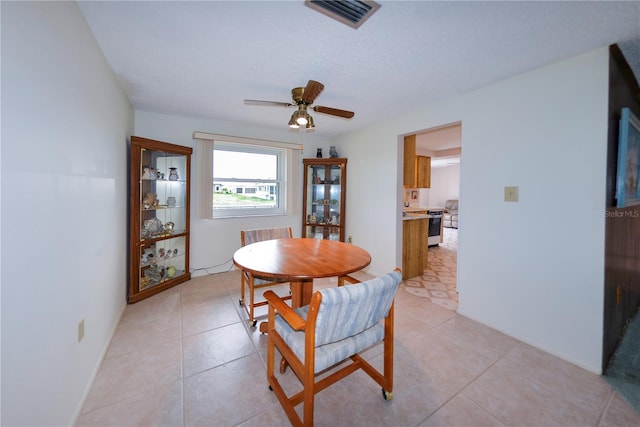 tiled dining room with a textured ceiling and ceiling fan