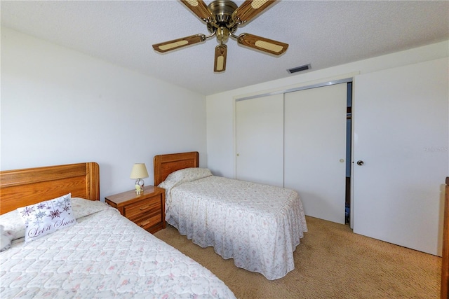 carpeted bedroom featuring ceiling fan, a textured ceiling, and a closet