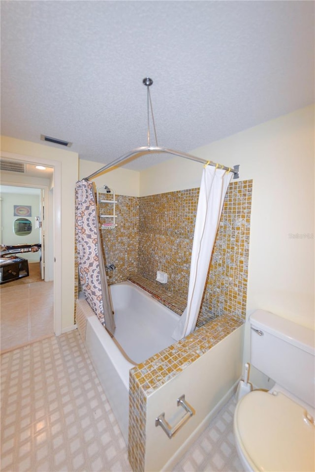 bathroom featuring toilet, shower / bath combo with shower curtain, and a textured ceiling