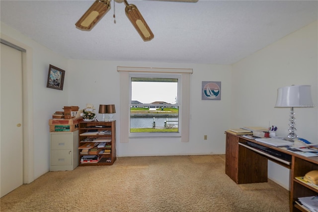 carpeted home office with ceiling fan and a water view