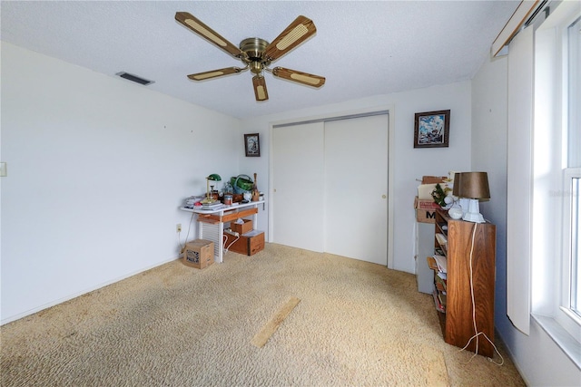 interior space with ceiling fan, a closet, carpet floors, and a textured ceiling