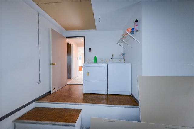 clothes washing area with parquet flooring and washer and clothes dryer