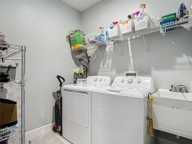 clothes washing area with light tile patterned floors, separate washer and dryer, and sink