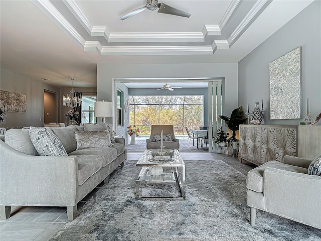 living room featuring a raised ceiling, tile patterned flooring, ornamental molding, and a notable chandelier