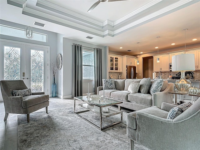 living room with french doors, ceiling fan, ornamental molding, a tray ceiling, and light tile patterned flooring