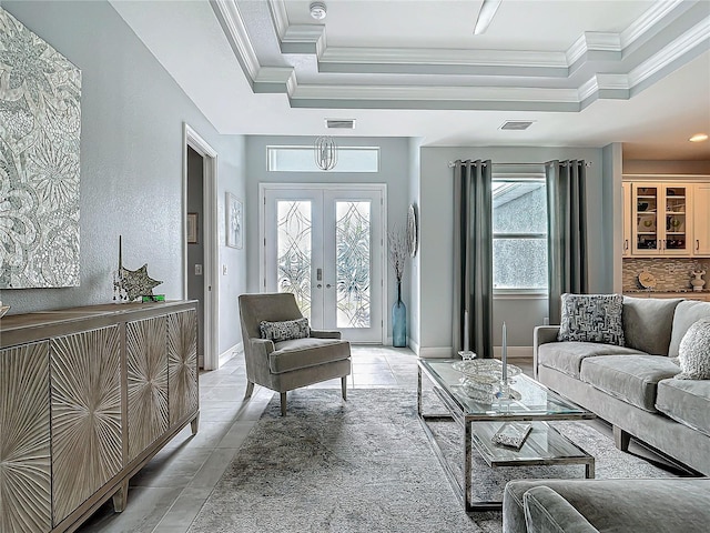 tiled living room with crown molding, a tray ceiling, and french doors