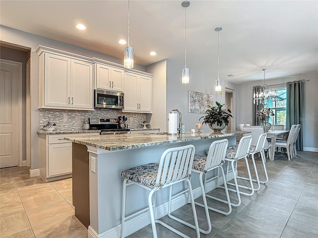 kitchen featuring decorative light fixtures, a spacious island, white cabinetry, and stainless steel appliances