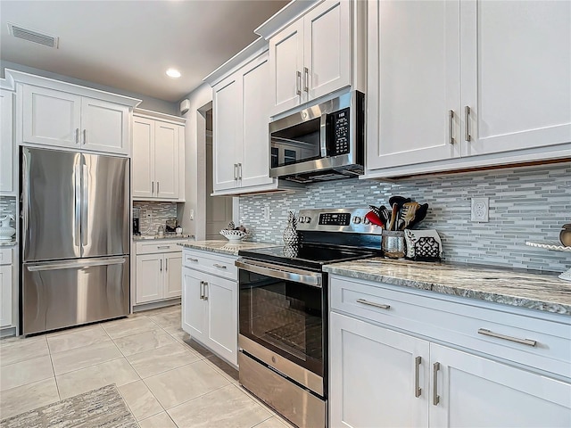 kitchen featuring tasteful backsplash, white cabinetry, light stone countertops, and appliances with stainless steel finishes