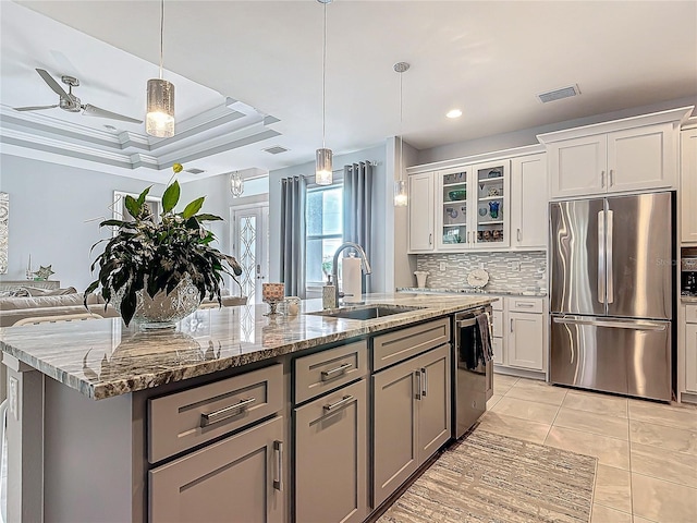 kitchen with pendant lighting, stainless steel appliances, white cabinetry, and a center island with sink