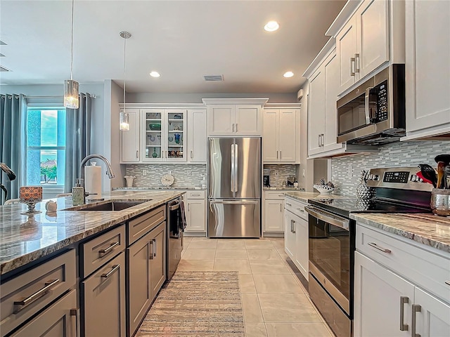 kitchen with dark stone countertops, sink, white cabinets, and appliances with stainless steel finishes