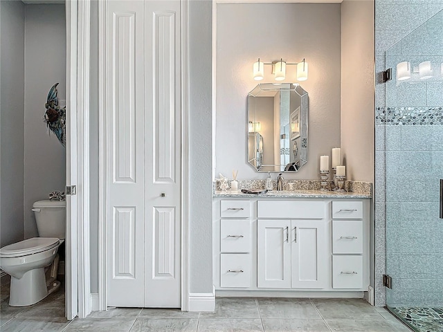 bathroom featuring tile patterned flooring, vanity, toilet, and a shower with shower door