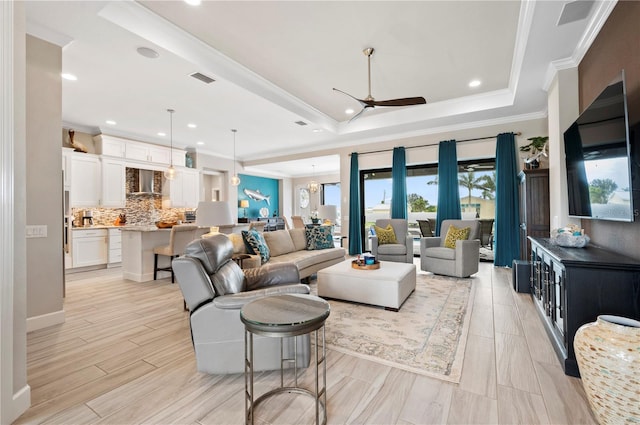 living room with a tray ceiling, ceiling fan, and ornamental molding