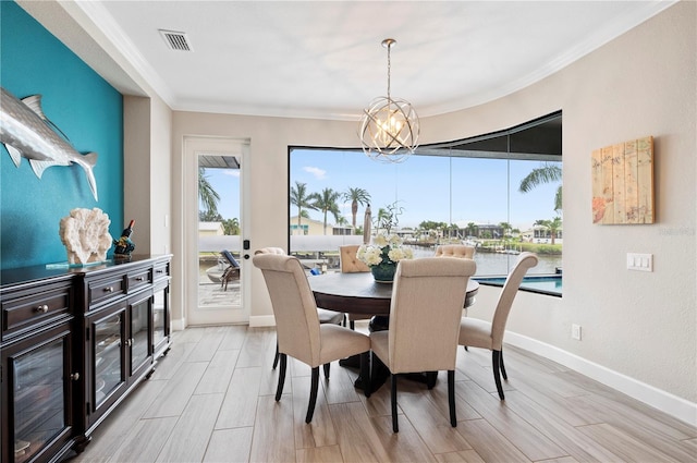 dining area featuring a water view, ornamental molding, and an inviting chandelier