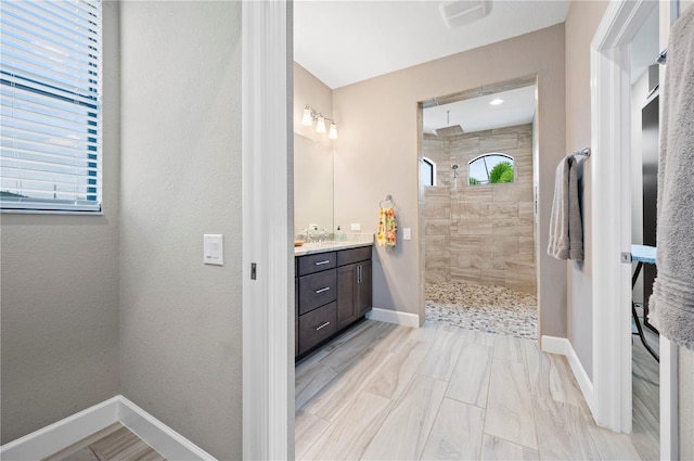 bathroom with a tile shower and vanity