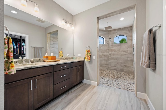 bathroom with a tile shower and vanity