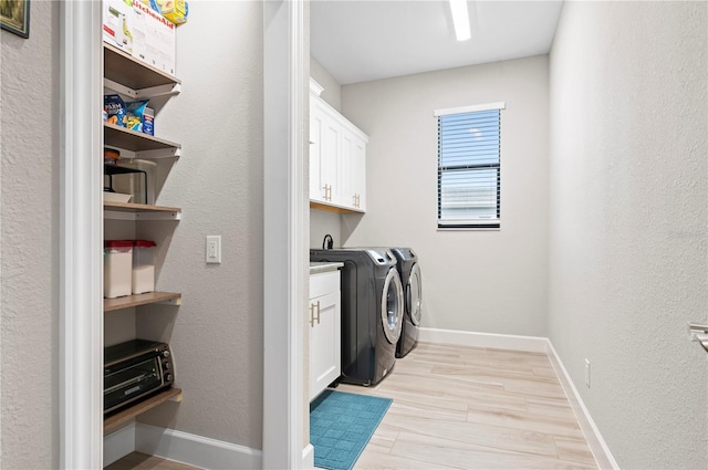 washroom with light hardwood / wood-style floors, cabinets, and washing machine and clothes dryer