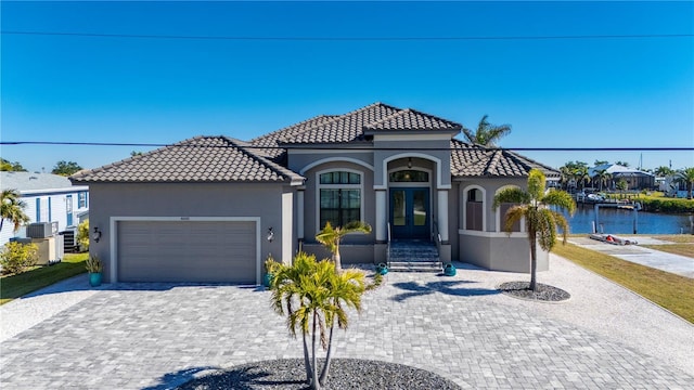 mediterranean / spanish-style house with a garage, a water view, and central air condition unit