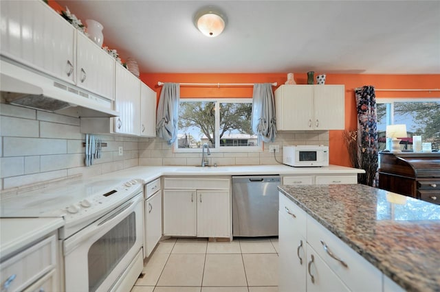 kitchen featuring light tile patterned floors, white appliances, white cabinetry, and backsplash