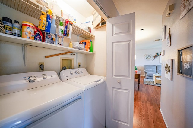 clothes washing area with wood-type flooring and independent washer and dryer