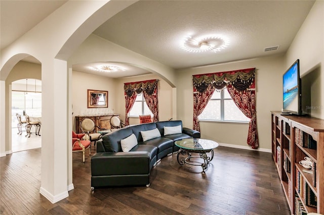 living room with a textured ceiling and dark wood-type flooring