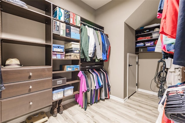 walk in closet with light hardwood / wood-style floors