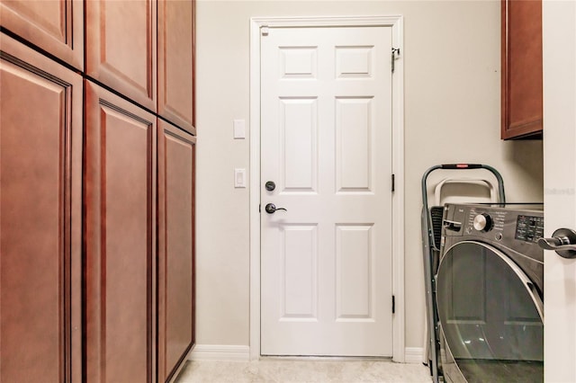 laundry area featuring cabinets, washer / dryer, and light tile patterned flooring