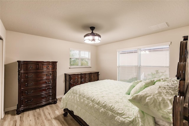 bedroom featuring a textured ceiling and light hardwood / wood-style flooring