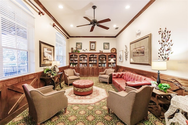 living room with ceiling fan, wood walls, and crown molding