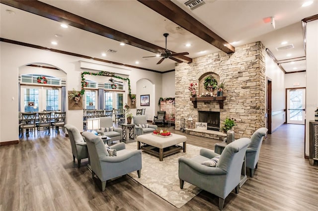 living room featuring a stone fireplace, ceiling fan, hardwood / wood-style floors, and crown molding