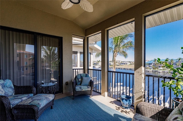 sunroom featuring lofted ceiling, ceiling fan, and a water view