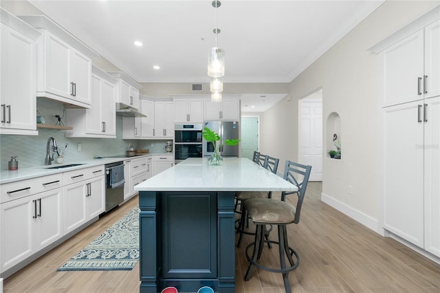 kitchen featuring sink, a center island, hanging light fixtures, appliances with stainless steel finishes, and white cabinets