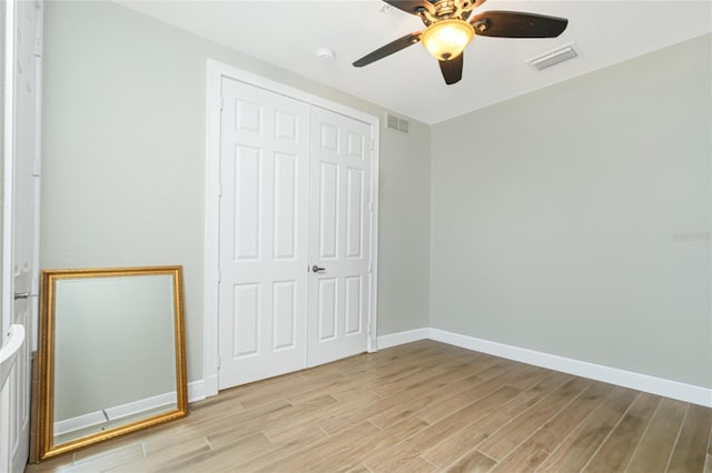 unfurnished bedroom featuring ceiling fan, light hardwood / wood-style floors, and a closet