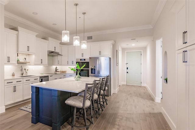 kitchen with white cabinetry, appliances with stainless steel finishes, sink, and pendant lighting