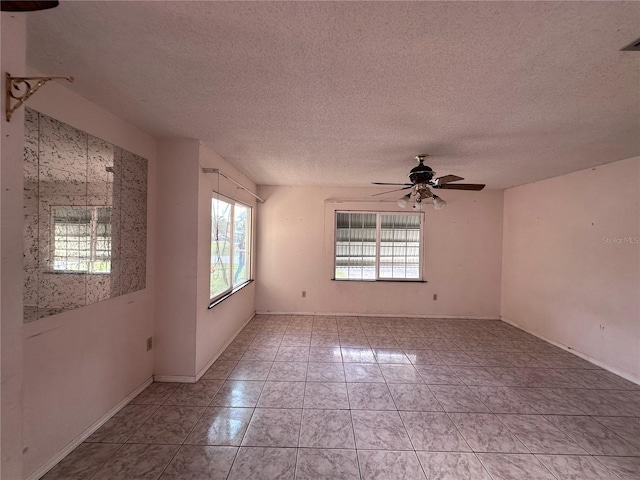 tiled empty room with ceiling fan and a textured ceiling