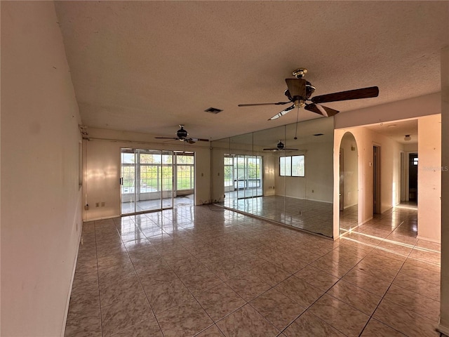 tiled empty room featuring a textured ceiling and ceiling fan