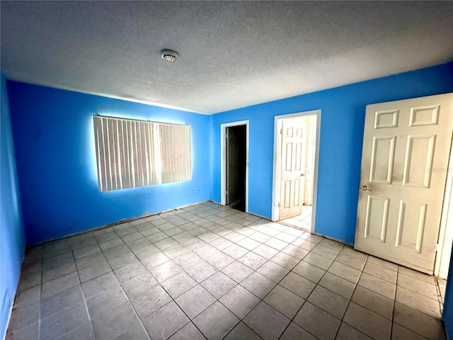 unfurnished bedroom with light tile patterned flooring, a textured ceiling, and a closet