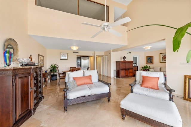 living room with ceiling fan and a high ceiling