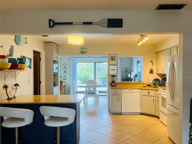 kitchen featuring butcher block countertops, white appliances, and white cabinetry