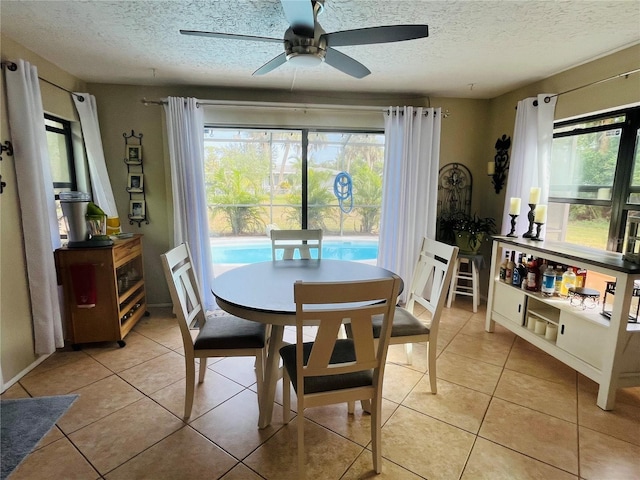 dining space with ceiling fan, a textured ceiling, and light tile patterned flooring