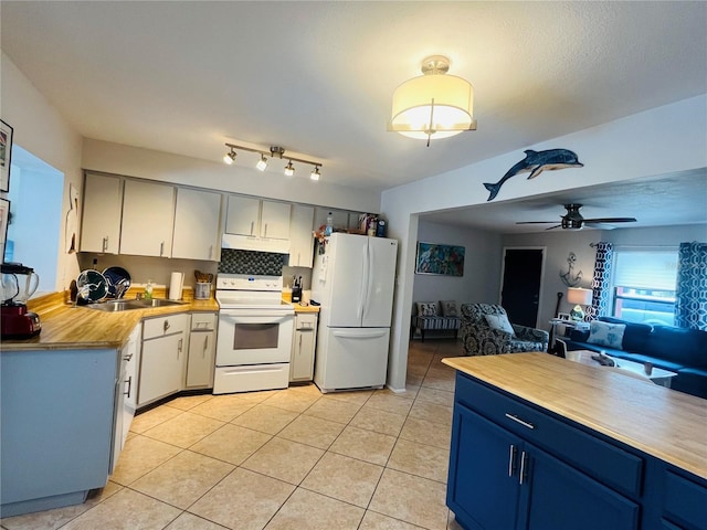 kitchen with sink, blue cabinetry, tasteful backsplash, and white appliances