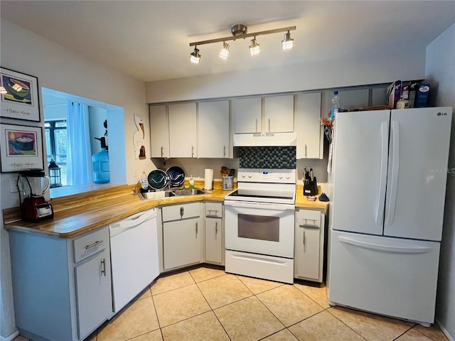 kitchen featuring light tile patterned floors, sink, backsplash, and white appliances