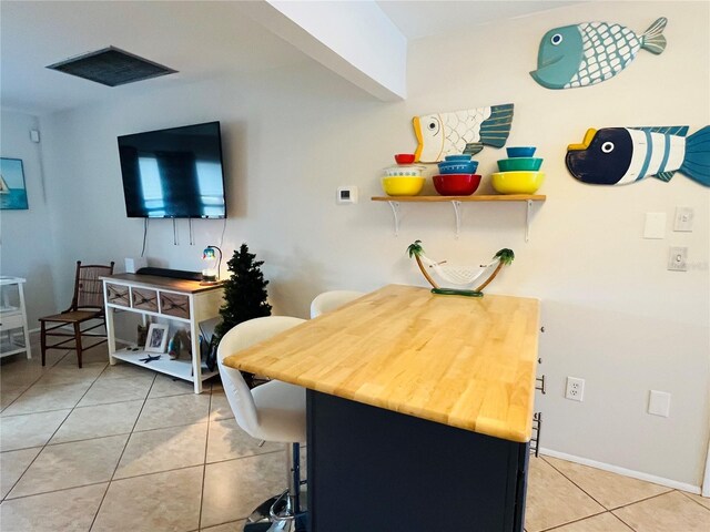 kitchen with light tile patterned floors, a kitchen bar, and kitchen peninsula