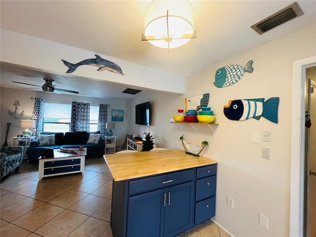 kitchen with ceiling fan, tile patterned flooring, wood counters, and blue cabinetry