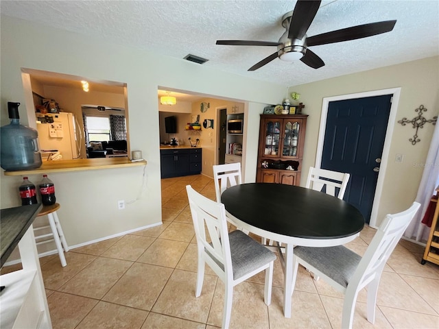 tiled dining room featuring a textured ceiling and ceiling fan