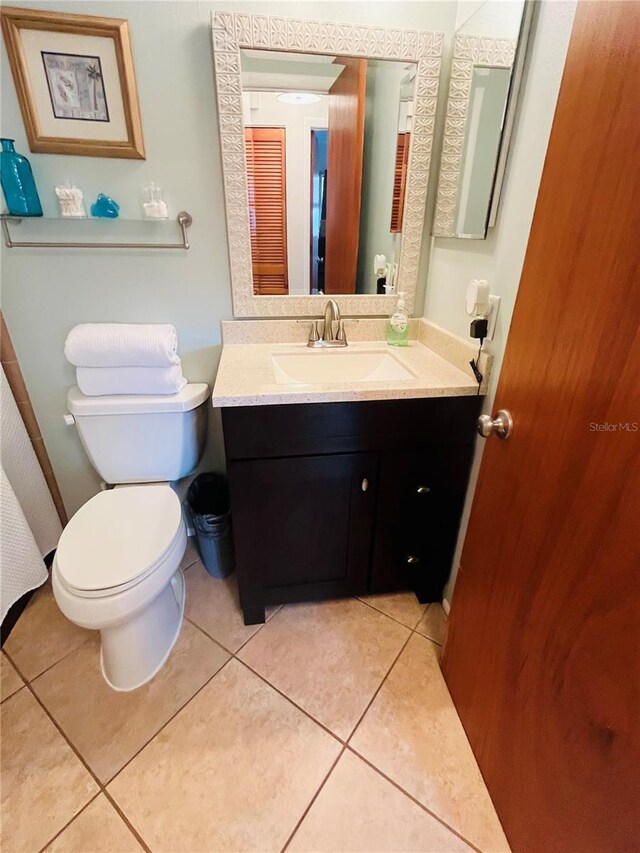 bathroom with toilet, vanity, and tile patterned floors