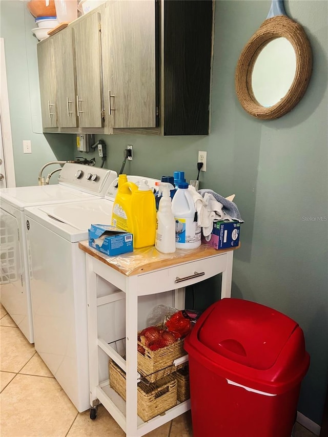 laundry area featuring washer and dryer, cabinets, and light tile patterned flooring