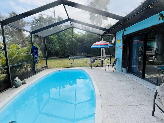 view of swimming pool featuring glass enclosure, a yard, and a patio