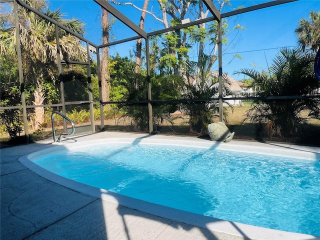 view of pool featuring glass enclosure and a patio area