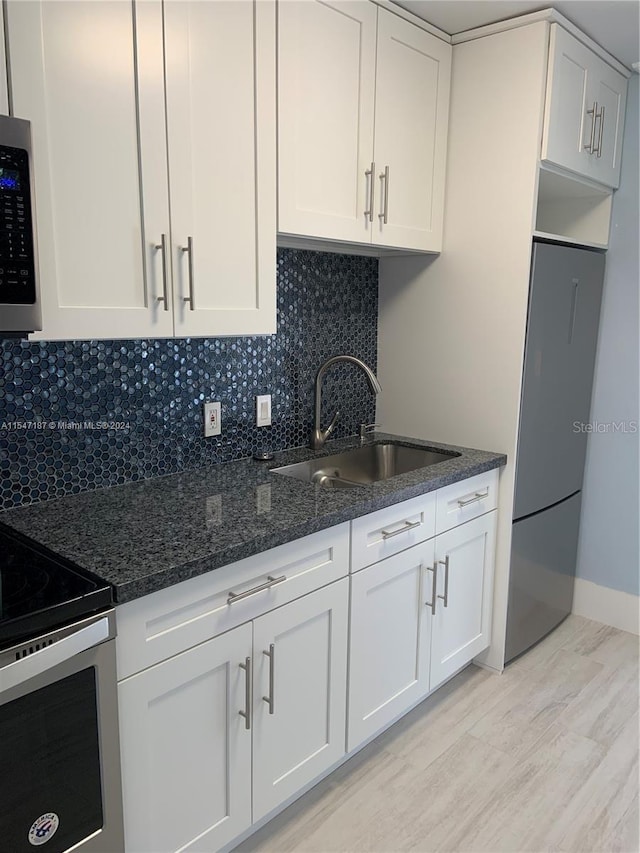 kitchen featuring tasteful backsplash, dark stone counters, sink, electric range, and white cabinetry