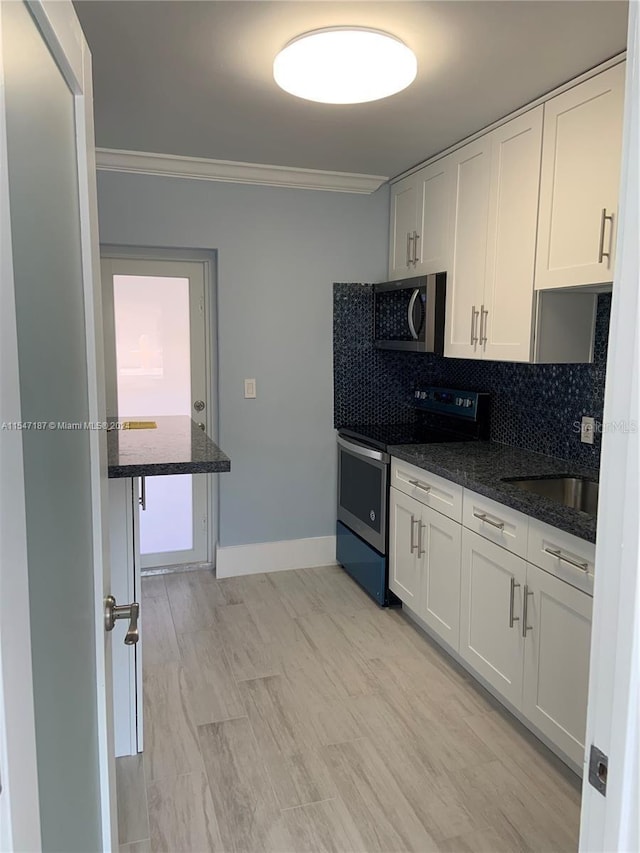 kitchen featuring tasteful backsplash, dark stone countertops, white cabinets, and appliances with stainless steel finishes